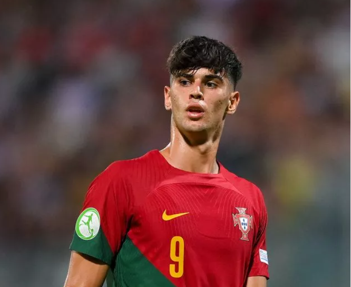 Jugador de la selección nacional de fútbol de Portugal, con el número 9, observa con expresión concentrada durante un partido.
Viste el uniforme oficial rojo y verde, con el escudo de la federación en el pecho y el logotipo del Campeonato de Europa Sub-21 en la manga.