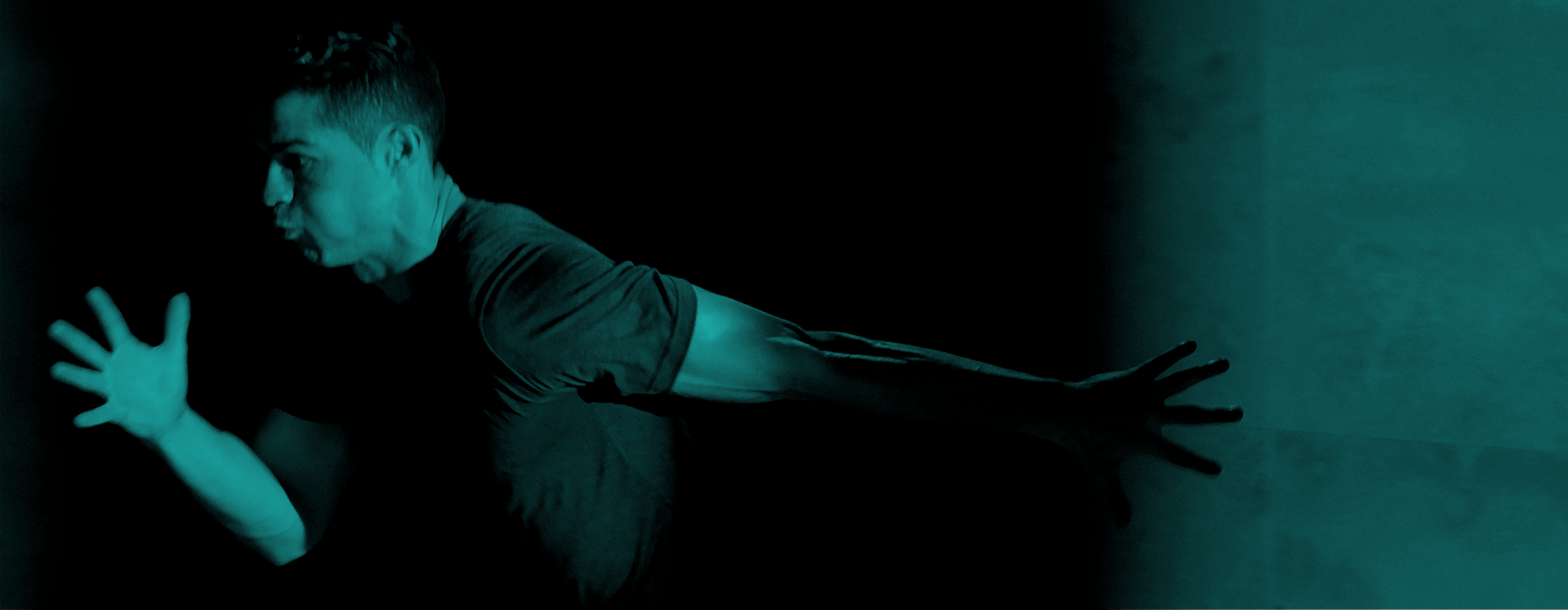 Jogador de futebol português, em movimento de corrida capturado com iluminação azul-esverdeada sobre fundo preto, expressando intensidade e foco físico.