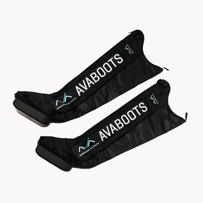 Par de botas de compressão AVABoots vazias e desinsufladas, dispostas em diagonal sobre fundo branco, com o logótipo AVABOOTS e a unidade compressora visível em cada bota.